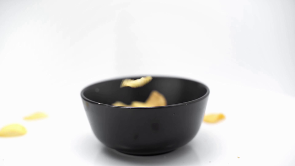 crispy chips falling into black bowl isolated on white - Filmagem, Vídeo