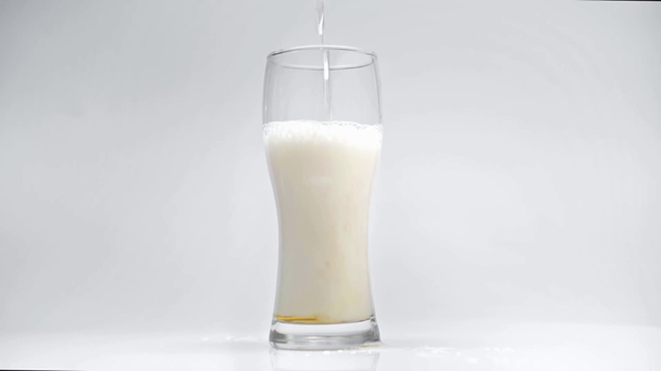 slow motion of light, fresh beer flowing into mug isolated on white - Felvétel, videó