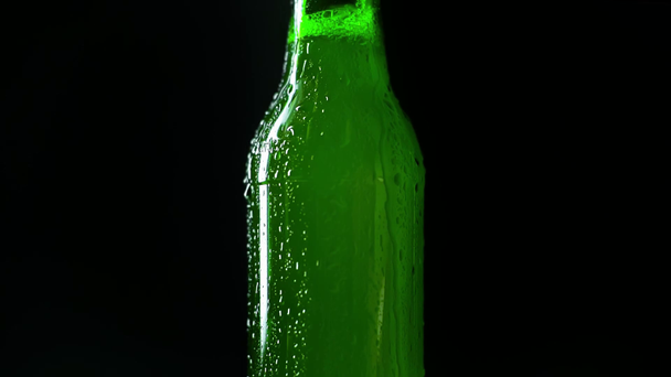 πράσινο μπουκάλι με ελαφριά μπύρα και συμπυκνωμένο νερό σταγόνες που απομονώνονται σε μαύρο - Πλάνα, βίντεο