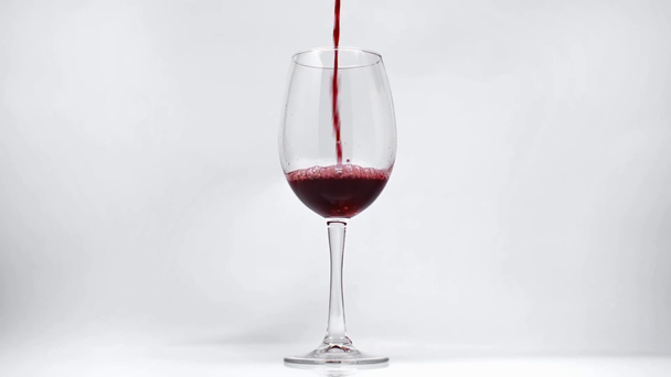 Zeitlupe von Rotwein, der in Weinglas auf Weiß gegossen wird  - Filmmaterial, Video