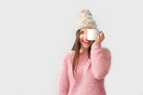 Beautiful happy young woman with cup of hot cocoa on light background - Zdjęcie, obraz