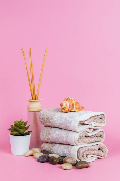 Spa essentials, aroma sticks stones, towels and a plant on a pink background - Valokuva, kuva