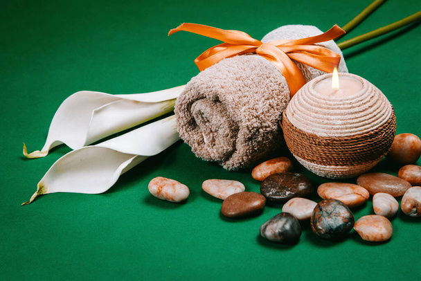 Essentials Spa, candele, pietre, asciugamani e fiori su sfondo verde scuro
 - Foto, immagini