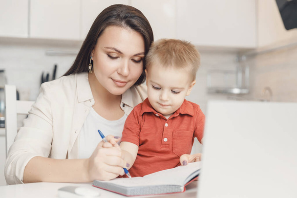 Η μητέρα μαθαίνει στον γιο της να γράφει στυλό. έννοια Online μάθηση καραντίνα - Φωτογραφία, εικόνα