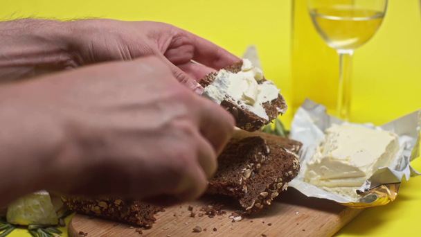 cropped view of man spreading butter on bread near bottle of wine  - Footage, Video