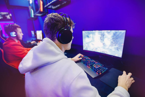 プロのゲーマーは、ヘッドフォン、赤と青でトーナメントオンラインビデオゲームコンピュータをプレイ - 写真・画像