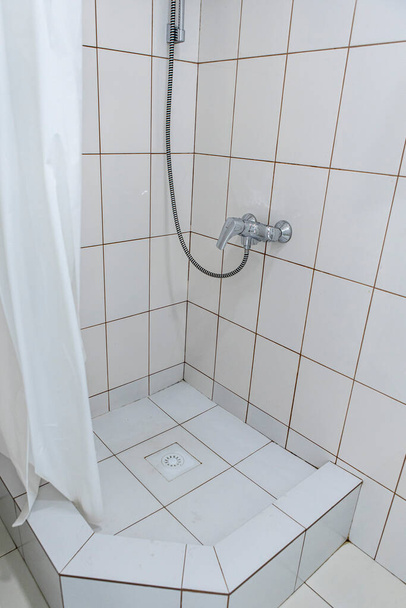 душова кімната з завісою в готелі, обшита білою плиткою
 - Фото, зображення
