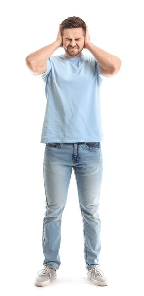 Young man suffering from loud noise on white background - Photo, Image