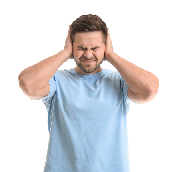 Young man suffering from loud noise on white background - Photo, Image