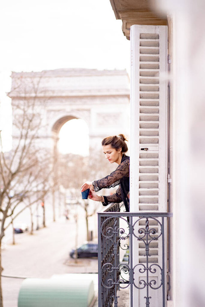 Attractive yang woman in pajama is drinking coffee on balcony  - Zdjęcie, obraz
