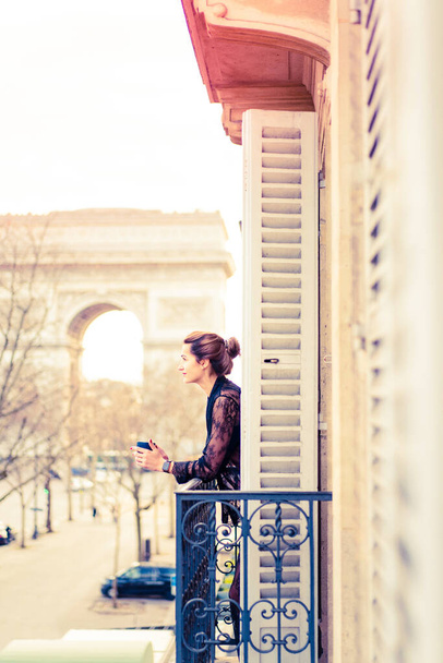 Attractive yang woman in pajama is drinking coffee on balcony  - Fotó, kép