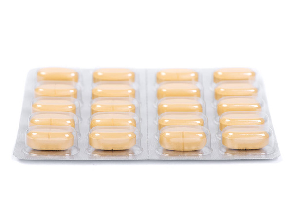 Pilules jaunes dans une plaquette isolée sur fond blanc - Photo, image