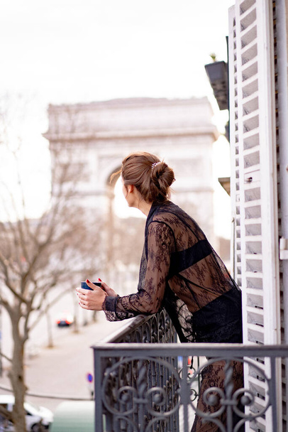Vonzó yang nő pizsamában kávét iszik az erkélyen  - Fotó, kép