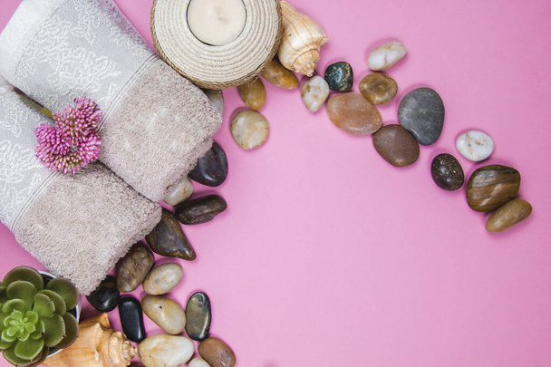 Spa essentials, aroma sticks stones, towels and a plant on a pink background - Photo, Image
