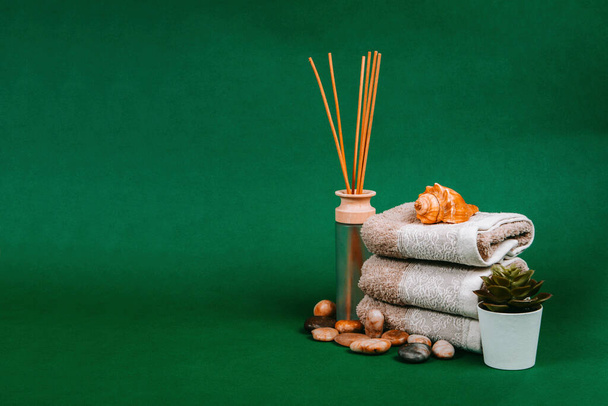 Spa essentials, candle, stones, towel and flowers on a dark green background - Foto, Imagem