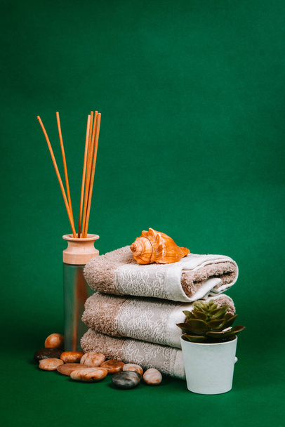Esenciales de spa, velas, piedras, toallas y flores sobre un fondo verde oscuro
 - Foto, imagen