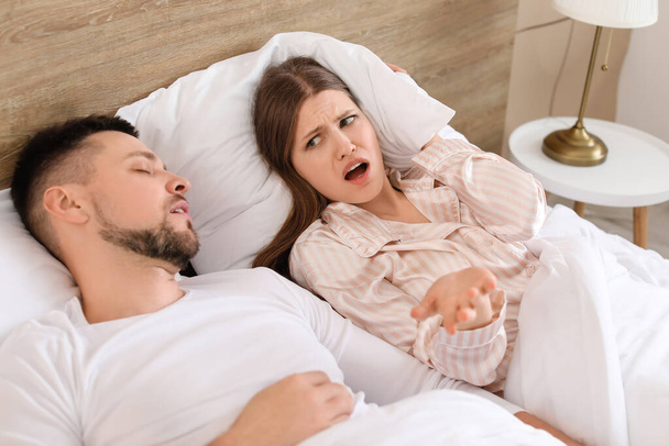 Jovem irritada mulher na cama com ronco marido em casa
 - Foto, Imagem