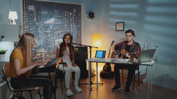Multiracial amateur band is rehearsing by singing playing keyboard and guitar - Fotó, kép