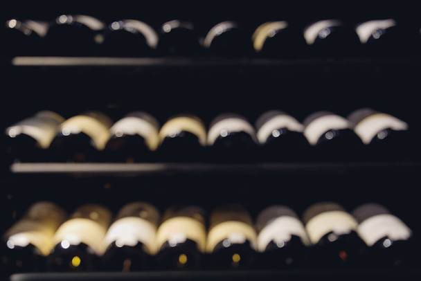 Розмитий фон скляних пляшок вина на інтер'єрі полиць в ресторані
 - Фото, зображення