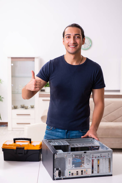 Młody człowiek naprawia komputer w domu - Zdjęcie, obraz