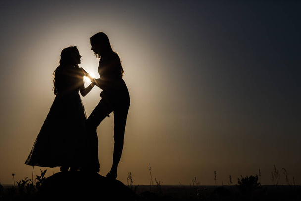 Two sisters are standing next to each other. Silhouettes. They perform different shapes. - Фото, зображення