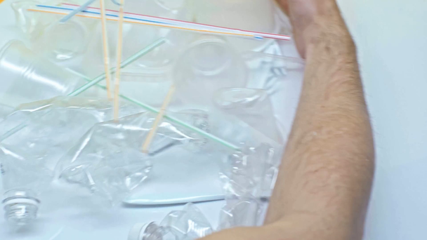cropped view of man sweeping away plastic cups and straws on white  - Footage, Video