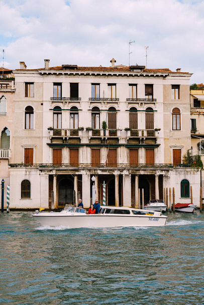 Venice, Italy - 04 october 2019: Tourists on the waterfront in Venice, against the background of the ancient facades of buildings standing in the water. Water sightseeing in Venice, Italy. - 写真・画像