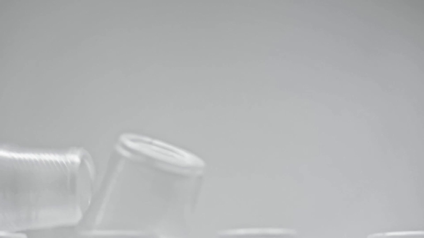 Αργή κίνηση πλαστικών κυπέλλων που πέφτουν απομονωμένα σε γκρι - Πλάνα, βίντεο
