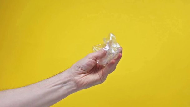 Iperlasso di uomo sbriciolamento bottiglia di plastica isolata su giallo
  - Filmati, video