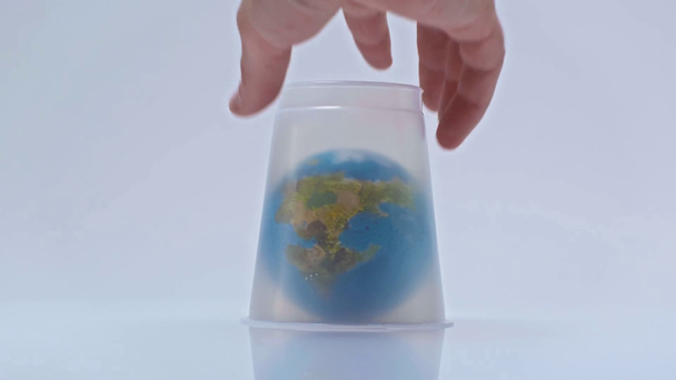 Küçük küreyi beyaz plastik bardakla kaplayan insan görüntüsü - Video, Çekim