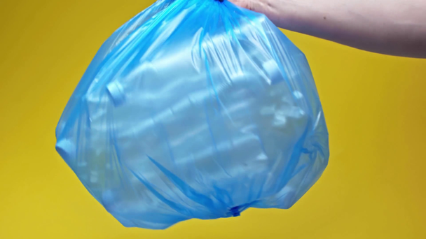 przycięty widok człowieka trzymając worek na śmieci z plastikowymi butelkami na żółto - Materiał filmowy, wideo