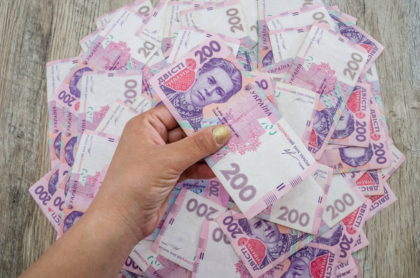 200 hryvnia in de hand tegen de achtergrond van hryvnia. - Foto, afbeelding