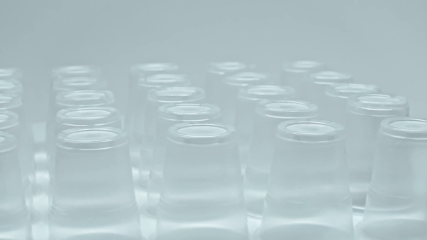 πλαστικά ποτήρια που περιστρέφονται απομονωμένα σε γκρι - Πλάνα, βίντεο
