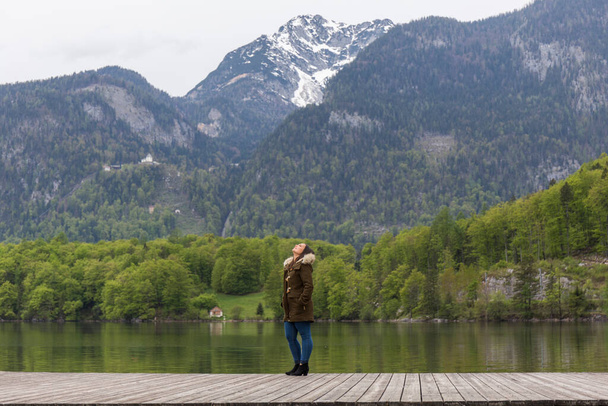 žena na dřevěném molu u jezera v rakouském tyrolsku v chladném a deštivém dni - Fotografie, Obrázek