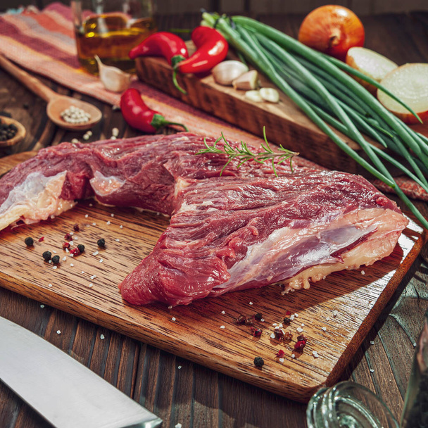Cauda de carne crua em uma tábua de corte com ingredientes
 - Foto, Imagem