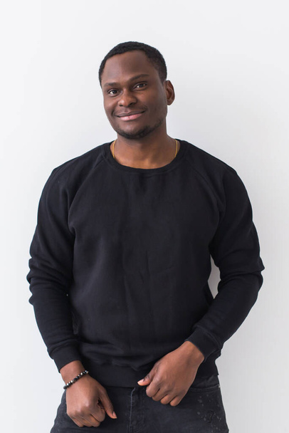 Youth street fashion concept - Portrait of confident sexy black man in stylish sweatshirt on white background. - Fotó, kép