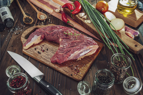 Raw beef rump tail on a cutting board with ingredients and knife - Photo, Image