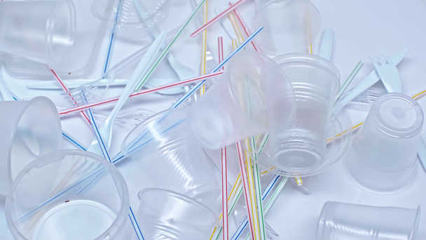 plastové kelímky padající na vidličky a slámy na bílém - Záběry, video