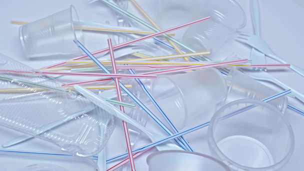 vista superior de copos de plástico perto de garfos e palhas em branco
 - Filmagem, Vídeo