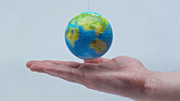 abgeschnittene Ansicht eines Menschen in der Nähe des Globus, der sich isoliert auf grau dreht  - Filmmaterial, Video