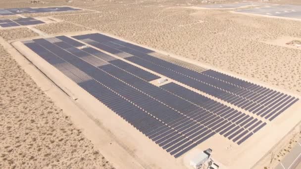 AÉRIAL : Un paysage aride entoure une grande ferme de panneaux solaires en Californie. - Séquence, vidéo