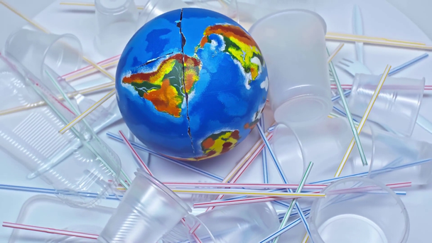globe near plastic cups, straws and forks on white  - Footage, Video