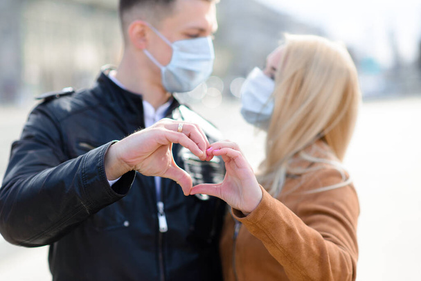 Jovem casal apaixonado em máscara médica protetora no rosto ao ar livre na rua. Guy e menina em proteção de vírus. - Foto, Imagem