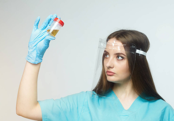 a female doctor holds a can of urine analysis in her hand - Foto, immagini