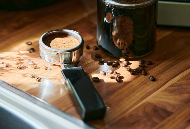 Кавовий порошок у мірній чашці для приготування еспресо вдома з кавовими зернами на задньому плані
. - Фото, зображення