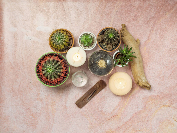 Top kilátás illatos tömjén pálca, különböző kaktusz és gyertyák rózsaszín homokos asztalon. - Fotó, kép