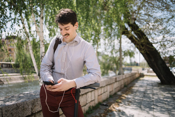 Happy man with headphones holding mobile phone while walking - Photo, image