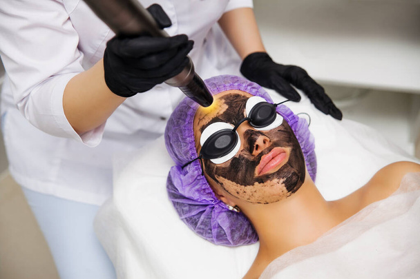 Processus d'épluchage laser de visage de carbone procédure dans le salon de beauté. Laser pulse peau propre du visage. Matériel traitement de cosmétologie. Rajeunissement de la peau du visage, réchauffement de la peau
 - Photo, image