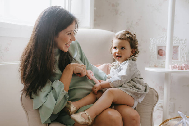 Jeune femme enceinte joue avec sa fille assise dans la chambre
 - Photo, image