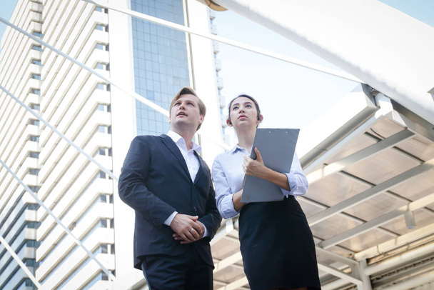 Male and female businessmen from different nationalities stand meeting outside the building. Entrepreneurial concept - 写真・画像